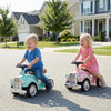 Kids riding in vintage-style sit-to-stand vehicles with working steering wheels and under-seat storage on a sunny.