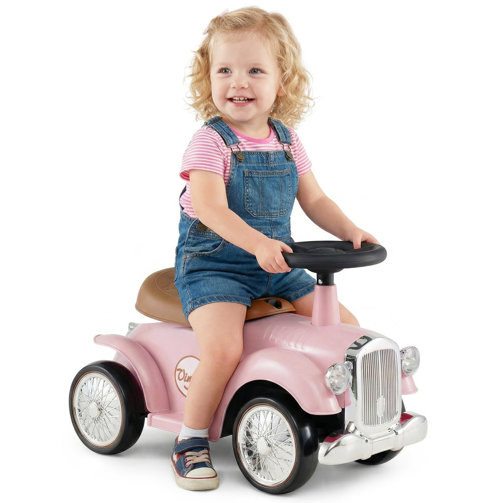 Kids sit-to-stand vehicle in pink with working steering wheel, under-seat storage, and vintage car styling for fun.