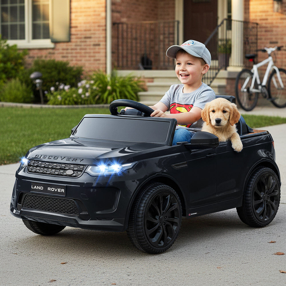 Licensed Land Rover kids ride-on car in black with a child and puppy, featuring bright lights and ergonomic seat.