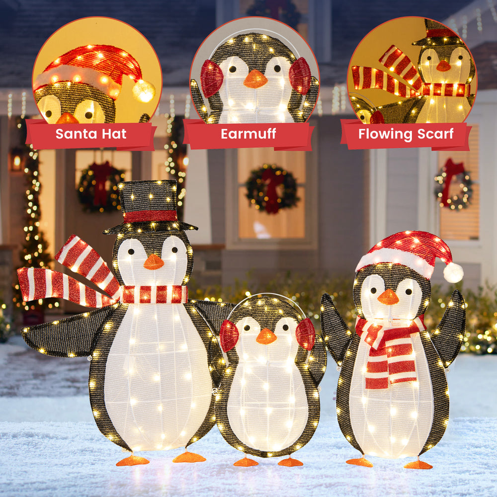 Three festive penguins with LED lights, wearing Santa hats and scarves, perfect for Christmas garden decorations.