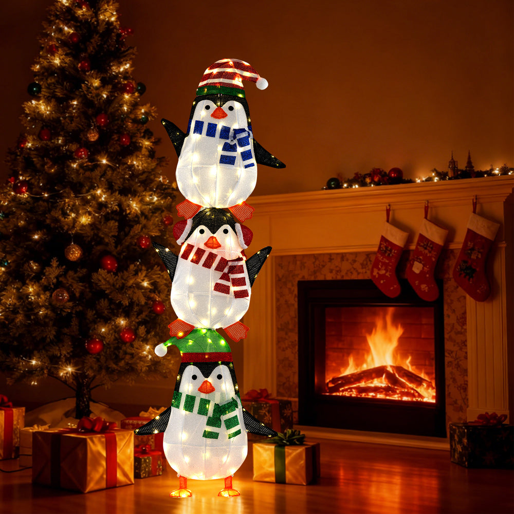 Three stacked penguins decoration with warm white lights and colorful hats, perfect for creating a festive indoor.
