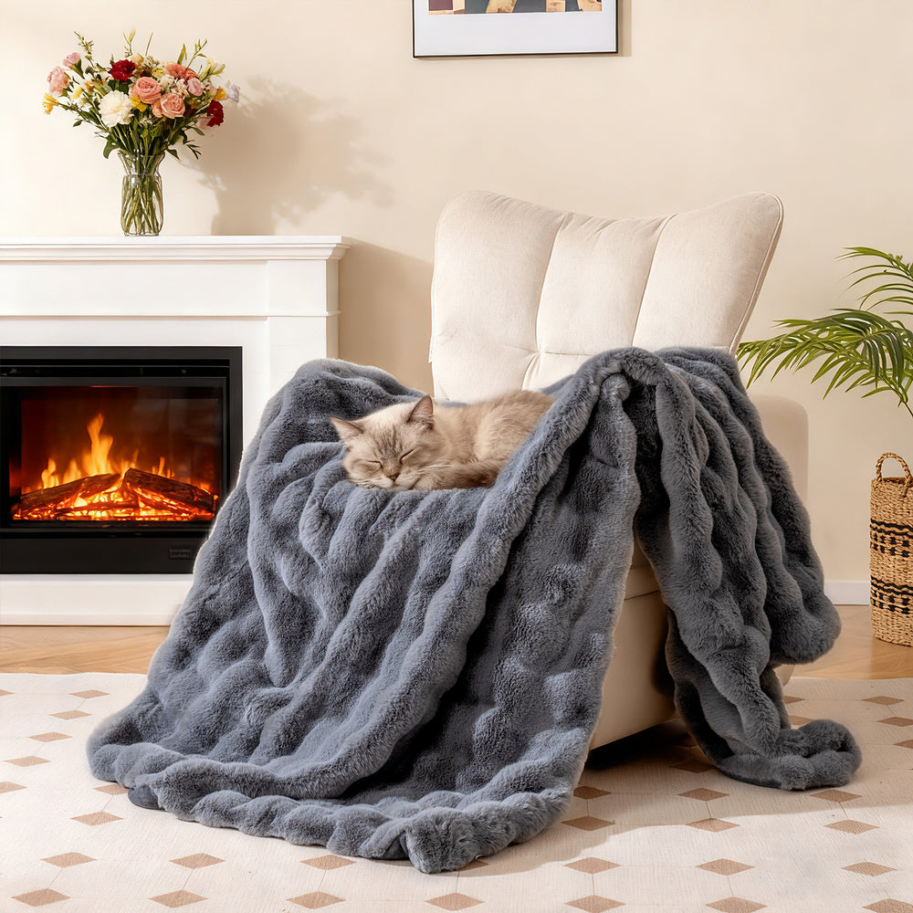 Luxury fuzzy plush rabbit fur bubble blanket in gray draped over an armchair, perfect for cozy warmth and comfort.