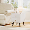 Mid Century Modern bedside table in white with golden knobs, featuring two drawers and raised support legs for easy.