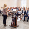 Height-adjustable mobile podium stand with tilting tabletop and storage compartments for presentations and meetings.