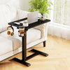 Height adjustable black mobile standing desk with cup holder, perfect for bedside or sofa use, featuring a spacious.