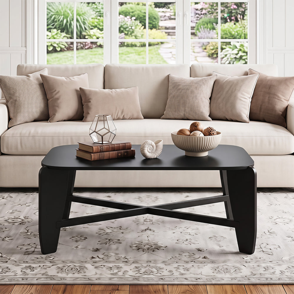 Rectangular black coffee table with rubber wood cross-leg base, designed for stability and enhanced safety with rounded edges.