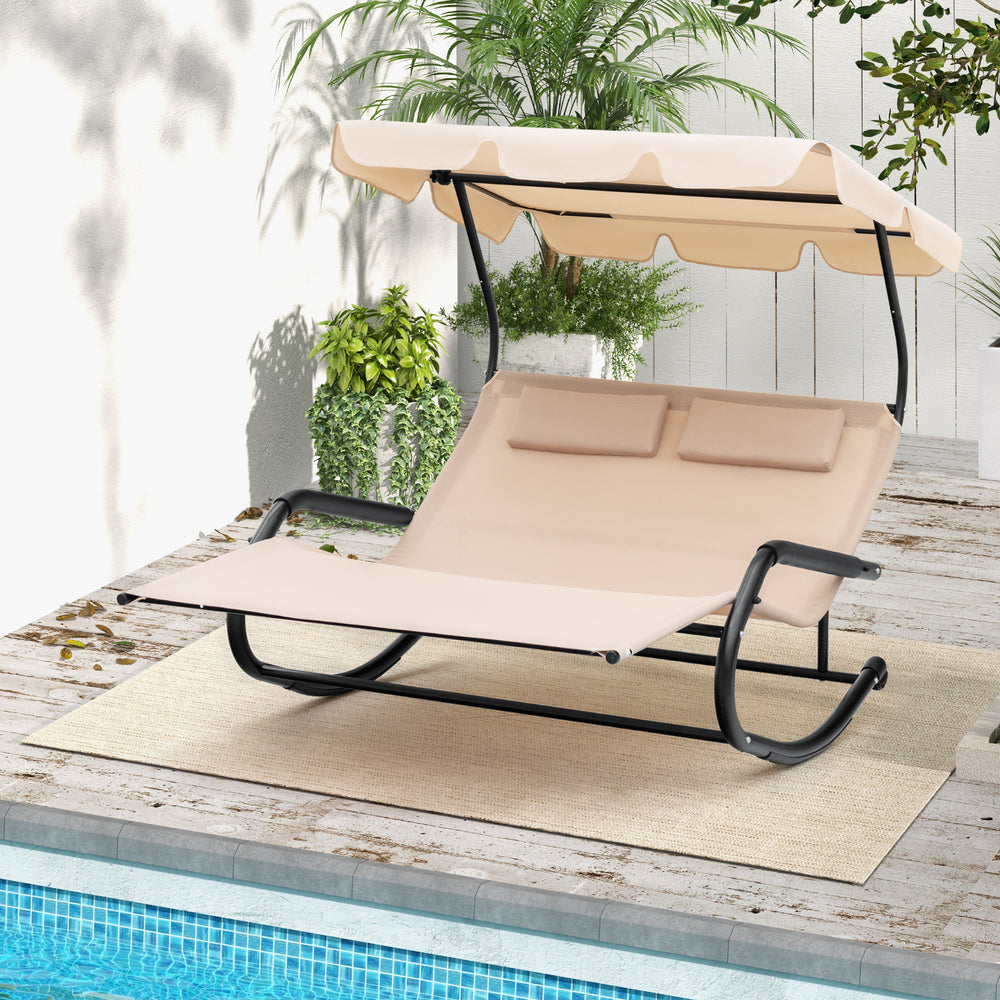Outdoor 2-person rocking chaise lounge in beige with adjustable canopy, perfect for poolside relaxation.