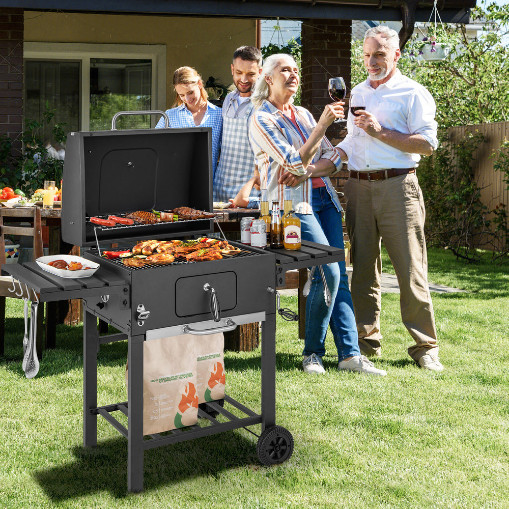 Outdoor BBQ charcoal grill with foldable side tables and wheels, perfect for large gatherings and easy grilling.