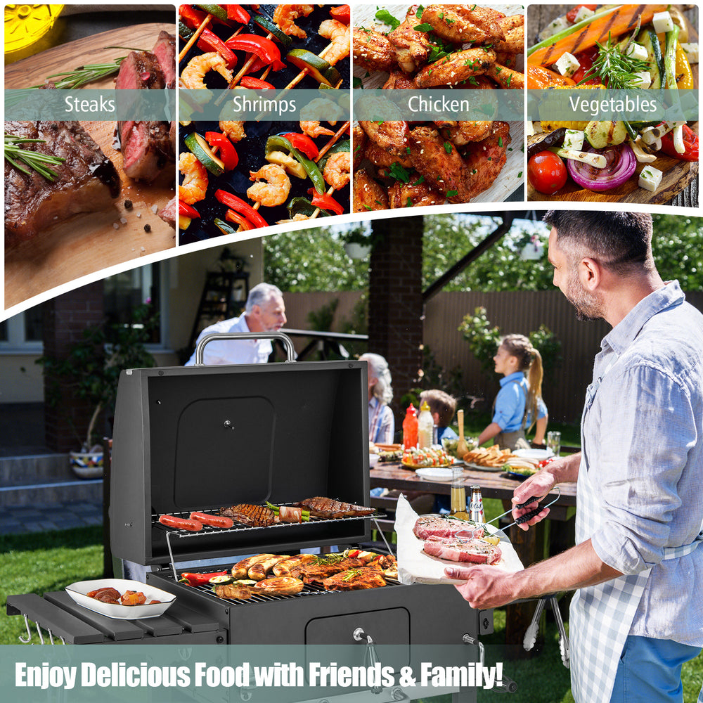 Outdoor BBQ charcoal grill with foldable side tables, large cooking area, and wheels for easy transport at a BBQ party.