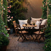 Outdoor bistro set featuring teak wood chairs and table, perfect for backyard relaxation and space-saving storage.