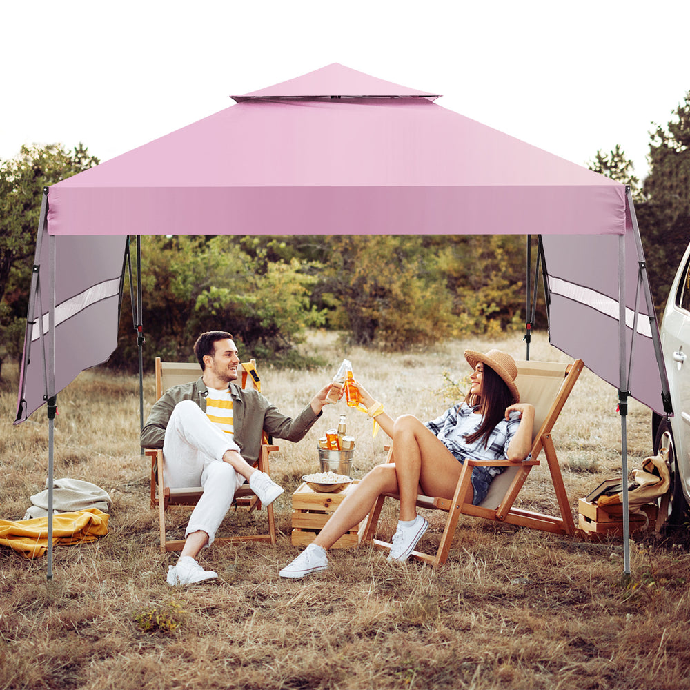 Outdoor instant pop-up canopy tent in pink with dual side awnings, perfect for beach picnics and family gatherings.