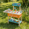 Wooden outdoor kids play kitchen set in orange with removable sink, featuring colorful food items and accessories.