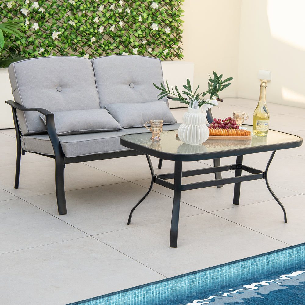 Outdoor loveseat chair set with soft cushions and a tempered glass coffee table, perfect for poolside relaxation.