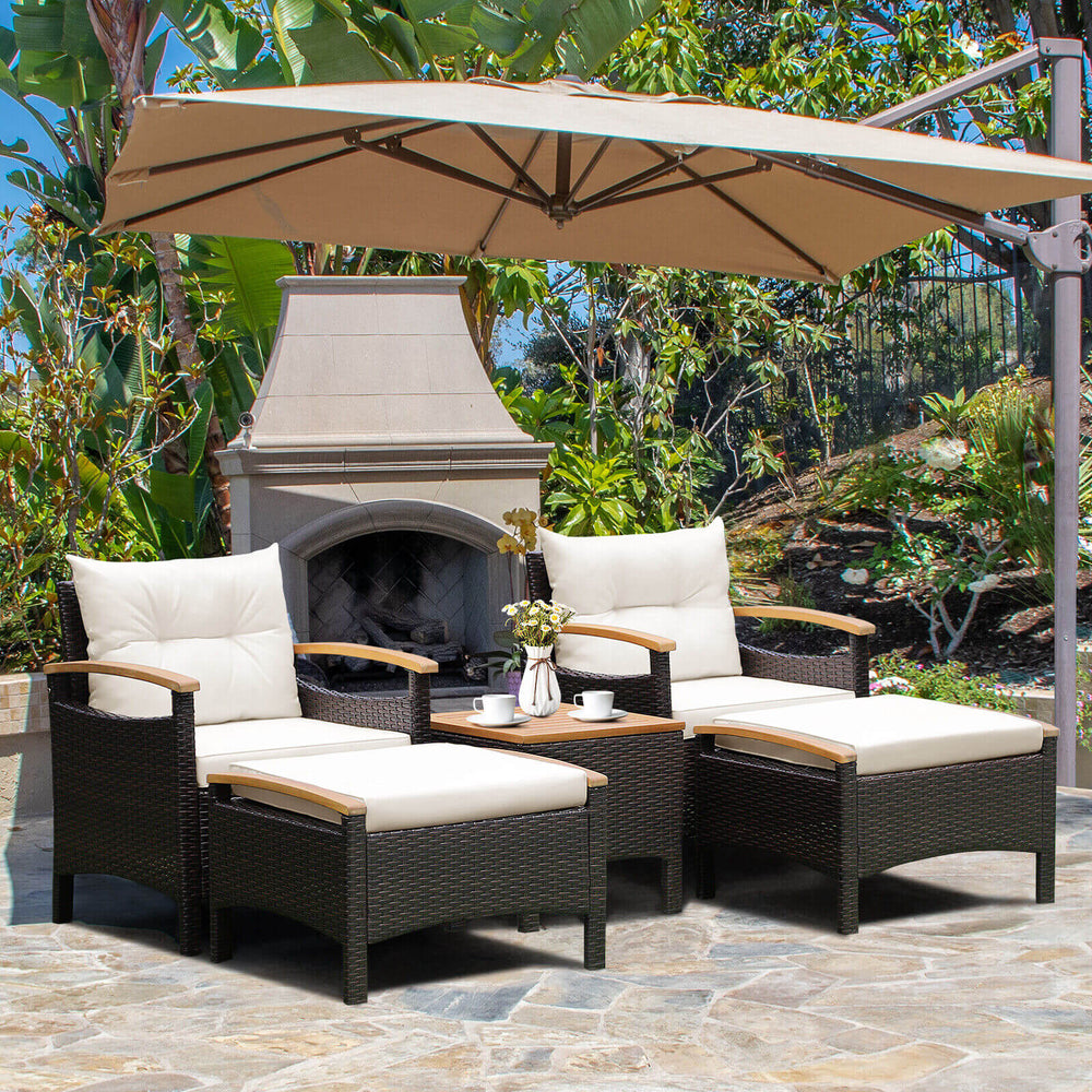 Patio conversation set featuring two chairs, ottomans, and a coffee table with cream cushions, ideal for outdoor.