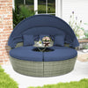 Round outdoor daybed with retractable canopy and navy cushions, perfect for backyard relaxation and sunbathing.