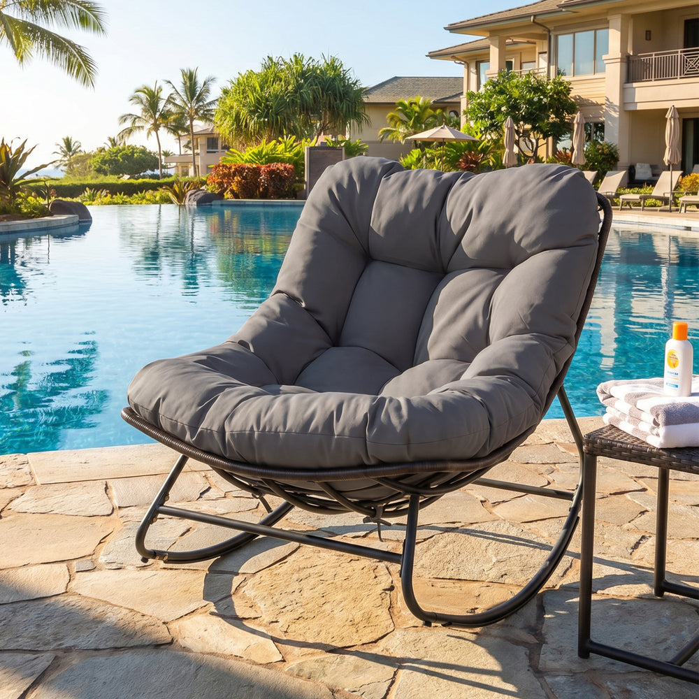 Outdoor Papasan rocking chair with gray cushion, ergonomic design, and stable metal frame for relaxing by the pool.