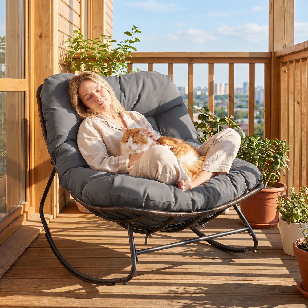 Outdoor Papasan rocking chair with thick gray cushion, providing ergonomic support and gentle rocking for relaxation.