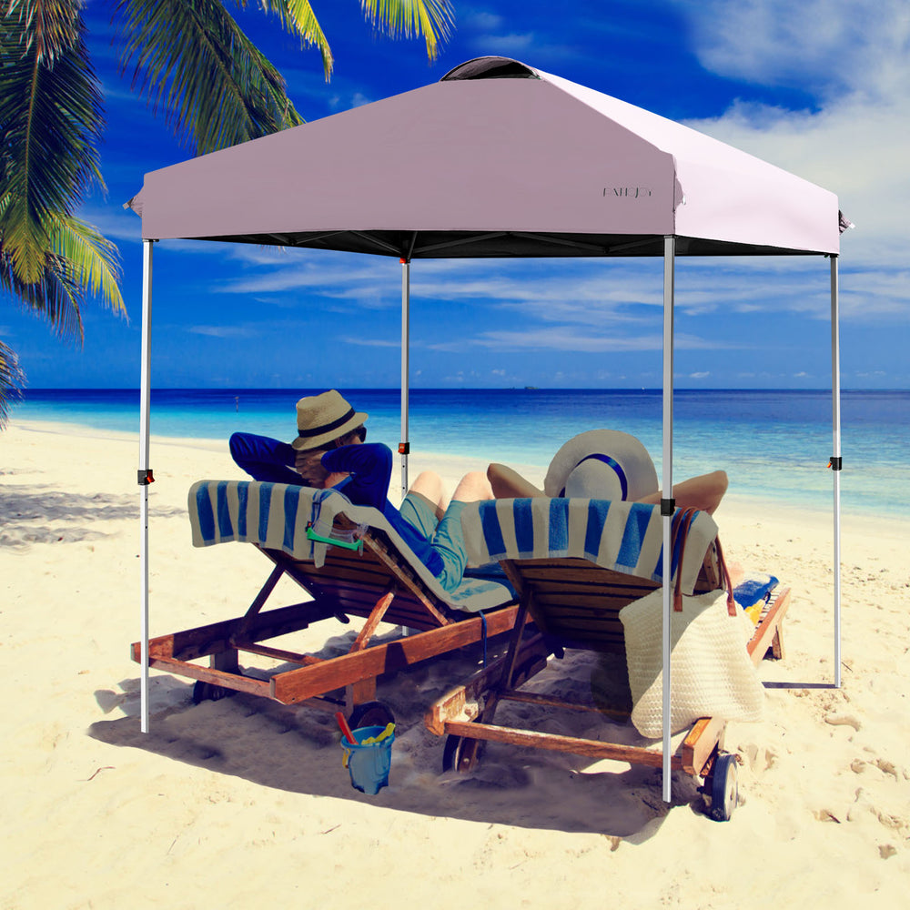 Outdoor pop-up canopy tent in pink, 6.6' x 6.6', adjustable height, providing shade for beach relaxation.