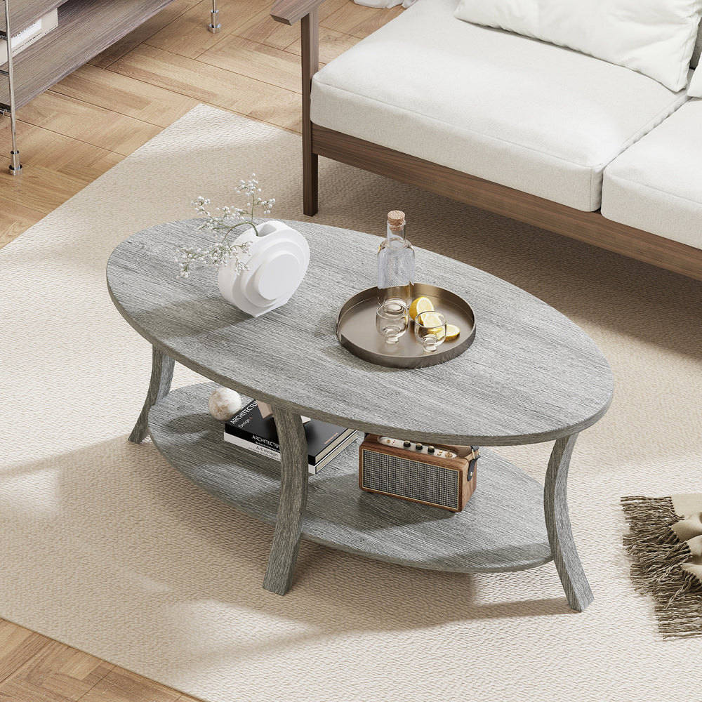 Oval coffee table in gray with a wide top and open storage shelf, perfect for snacks and magazines in any living space.