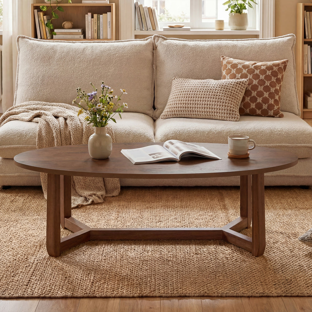 Oval coffee table with thickened walnut top and stable V-shaped base, perfect for snacks and decor in a cozy living.