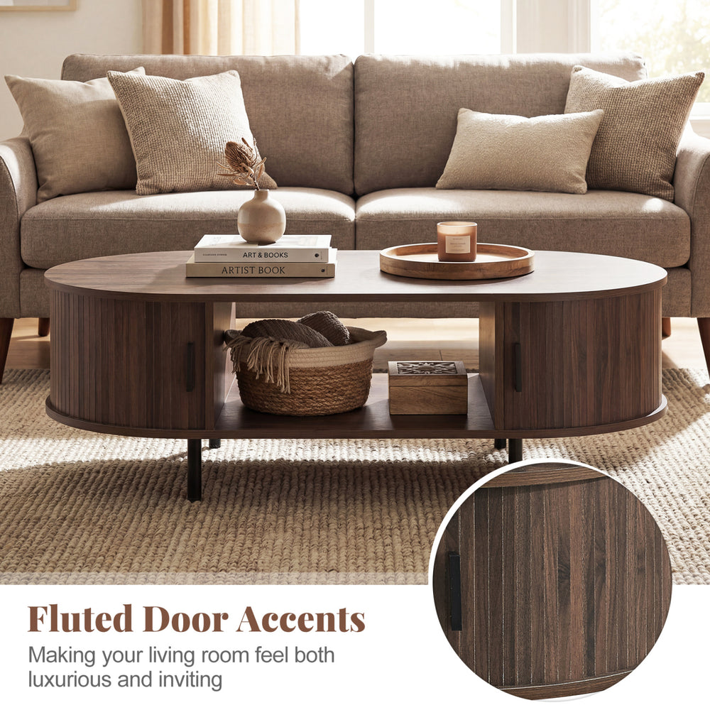 Oval coffee table with fluted door accents, walnut finish, and dual side shelves for stylish living room storage.