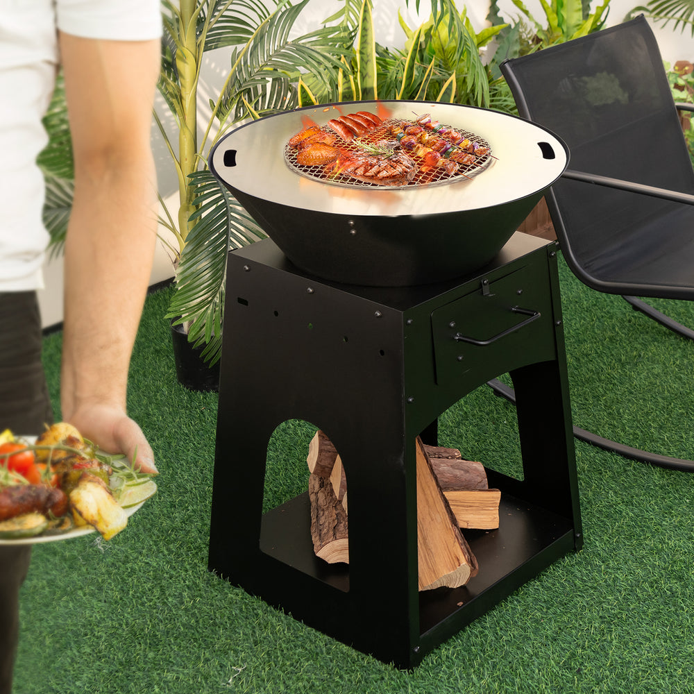 Patio fire pit with grill and ash box, featuring a black metal design and wood storage, ideal for outdoor gatherings.