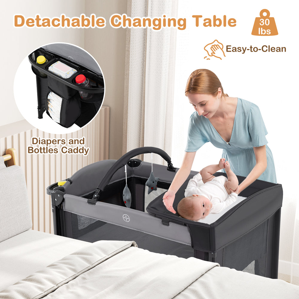 Detachable changing table on a foldable baby bassinet in gray, featuring adjustable heights and easy access for infants.