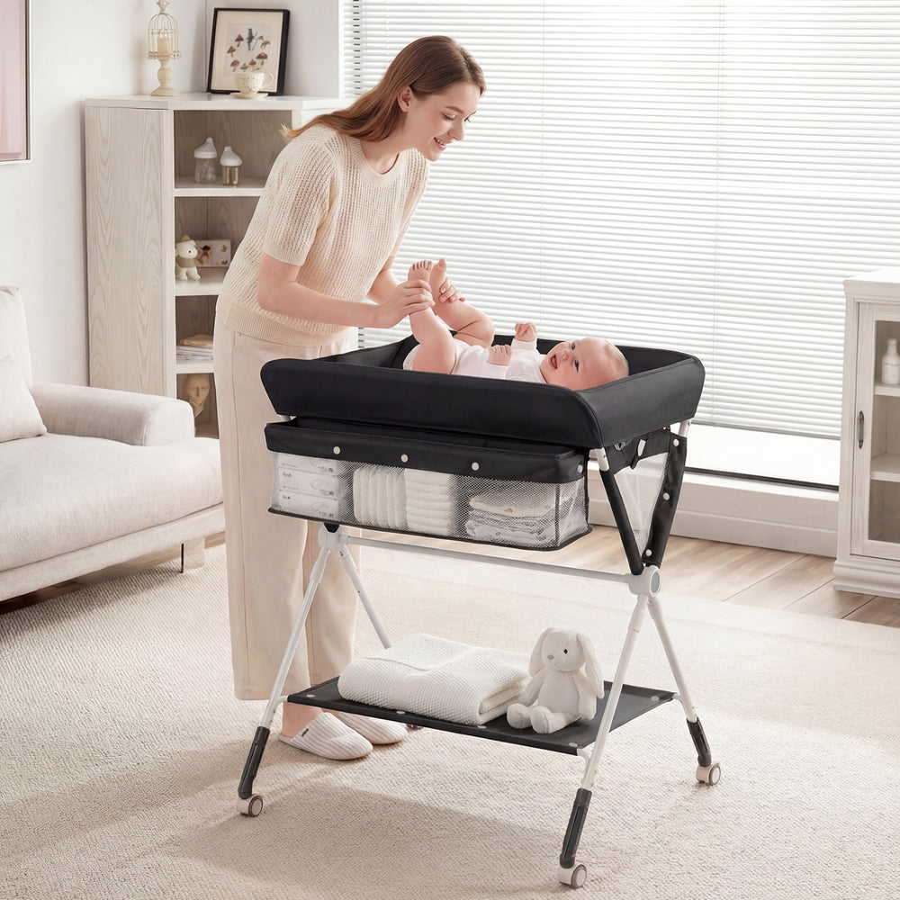 Portable baby changing table in black with adjustable height, featuring storage basket and protective mesh net.