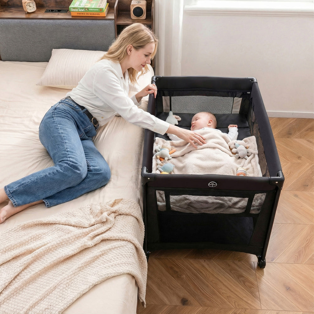 Portable baby playard in black with a soft mattress, perfect for infants and easy to fold for travel.