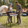 Portable charcoal grill with adjustable grate, spice rack, and carrying bag, ideal for camping and tailgating.