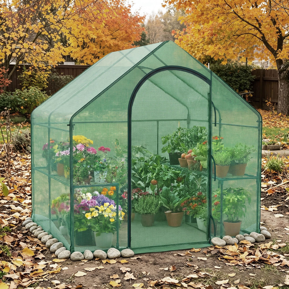 Portable outdoor warm house with PE cover shows vibrant plants inside, featuring a roll-up zippered door for easy access.