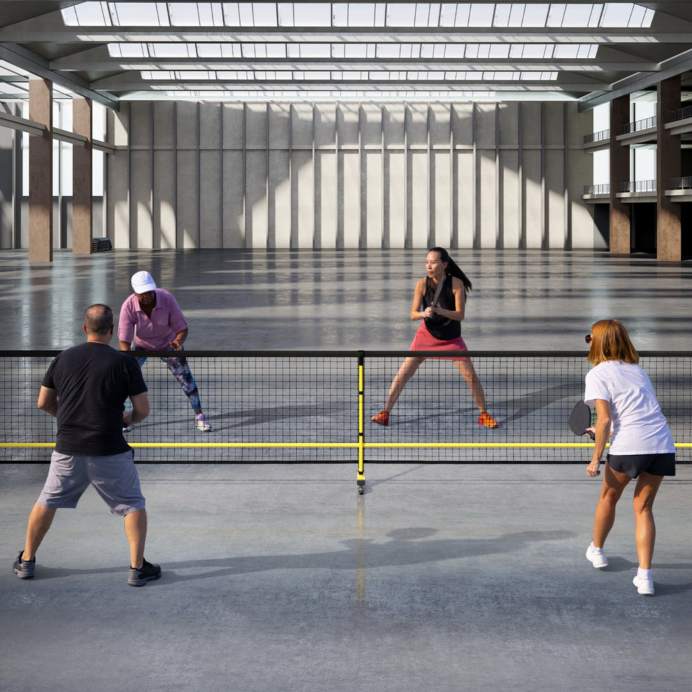 Portable 22 ft pickleball net with 6 lockable wheels, set up for play in a spacious indoor court environment.