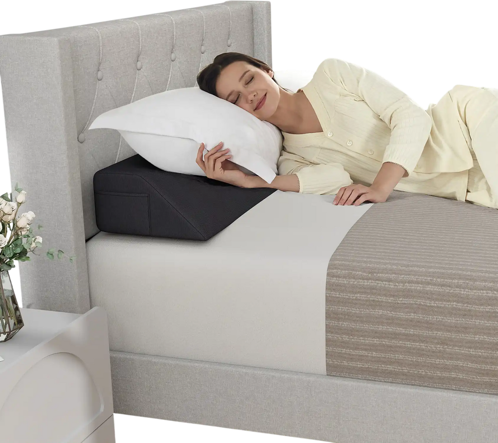 Bed wedge pillow in use, providing spinal support and filling gaps, with side storage pockets for essentials.
