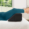Bed wedge pillow in use, supporting legs for optimal spinal alignment, with side storage pockets for convenience.