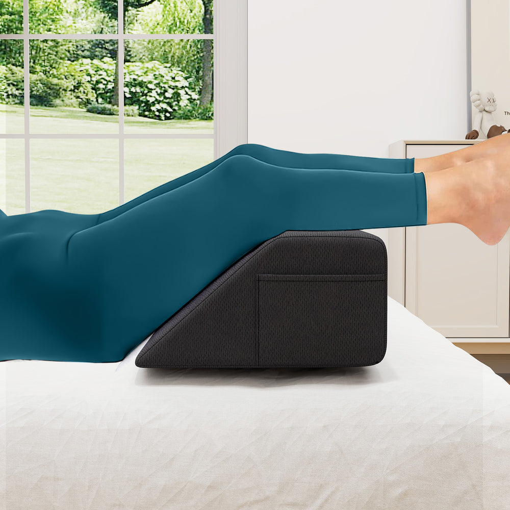 Bed wedge pillow in use, supporting legs for optimal spinal alignment, with side storage pockets for convenience.