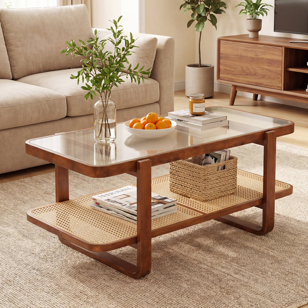 Rattan coffee table with tempered glass top and storage shelf in walnut finish, styled with decor and fruit bowl.