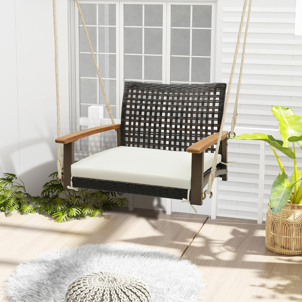 Single rattan porch swing with acacia wood armrests and white cushion, perfect for outdoor relaxation on the patio.