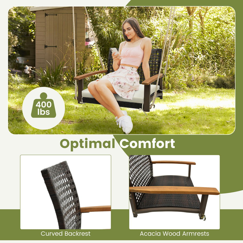 Single rattan porch swing with acacia wood armrests and cushion, designed for outdoor comfort and holds up to 400 lbs.