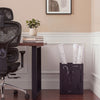 Black rectangular umbrella holder rack with removable drip tray, placed beside a desk in a stylish office setting.