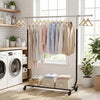 Extendable rolling clothes rack with hanging shirts and storage bins, ideal for laundry or bedroom organization.