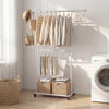 Double-rod extendable garment stand with hanging clothes, adjustable height, and storage baskets for versatile.