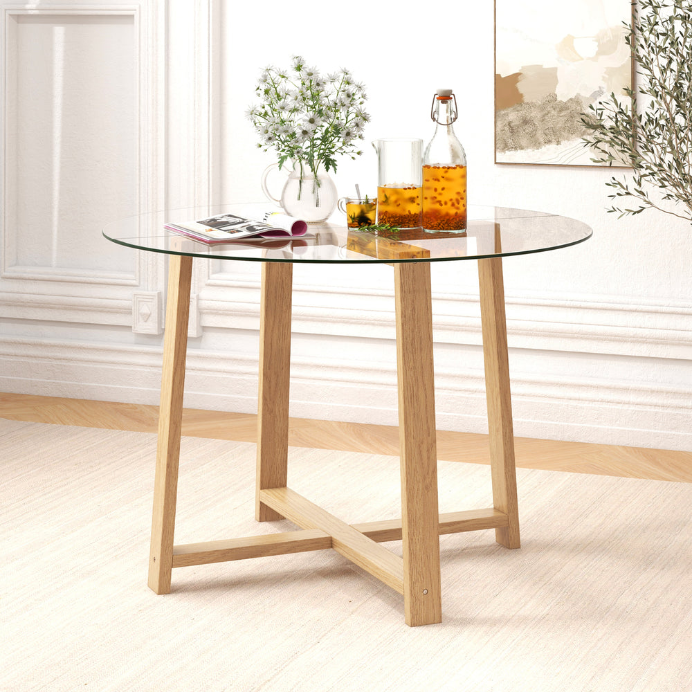 Round glass dining table featuring a natural rubber wood X-shaped frame, designed for stability and easy cleaning.