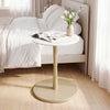 Round marble side table with stone finish and wooden base in white and gold, perfect for small spaces in a bedroom.