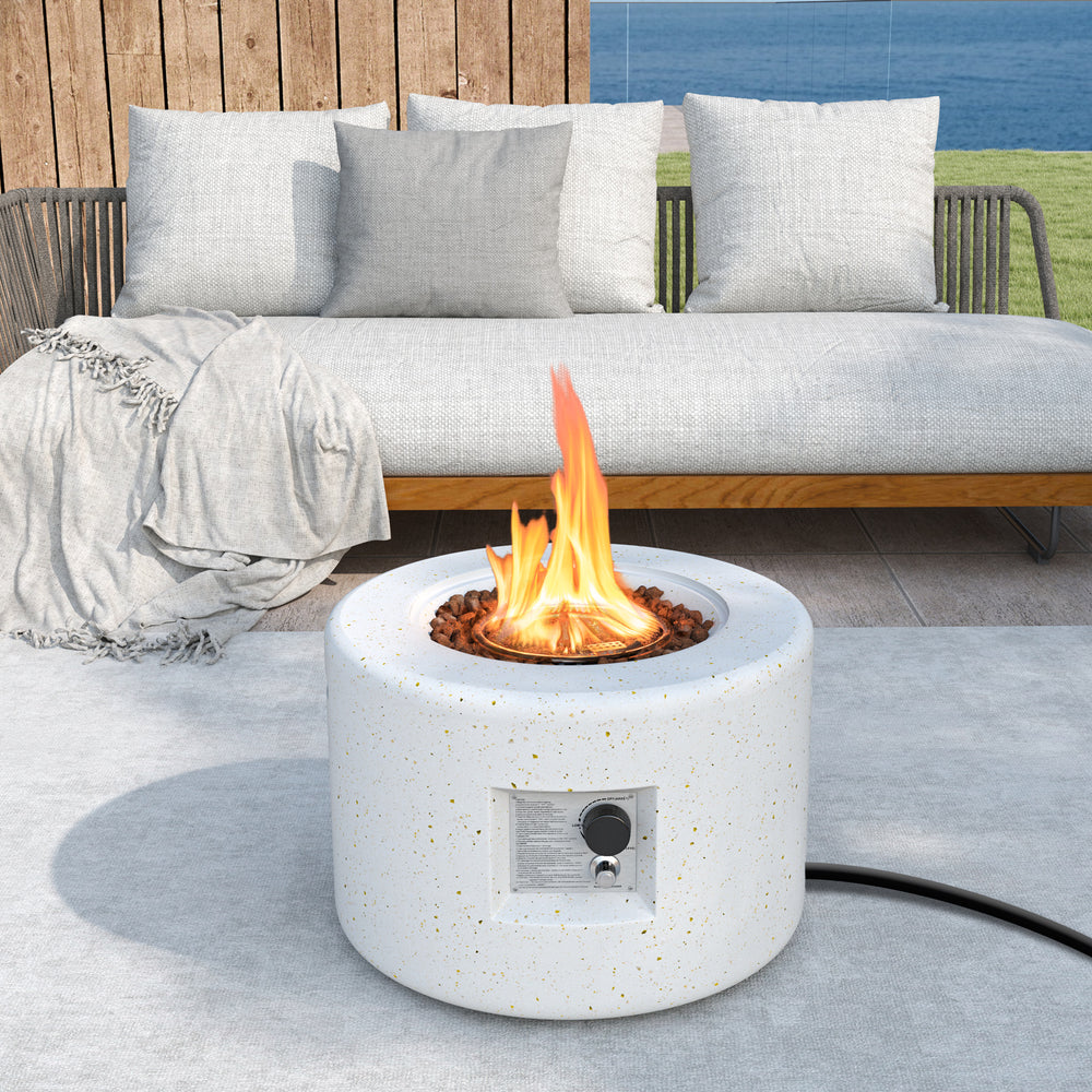 Round terrazzo propane gas fire pit with lava rocks, featuring a stylish white design for outdoor elegance and warmth.