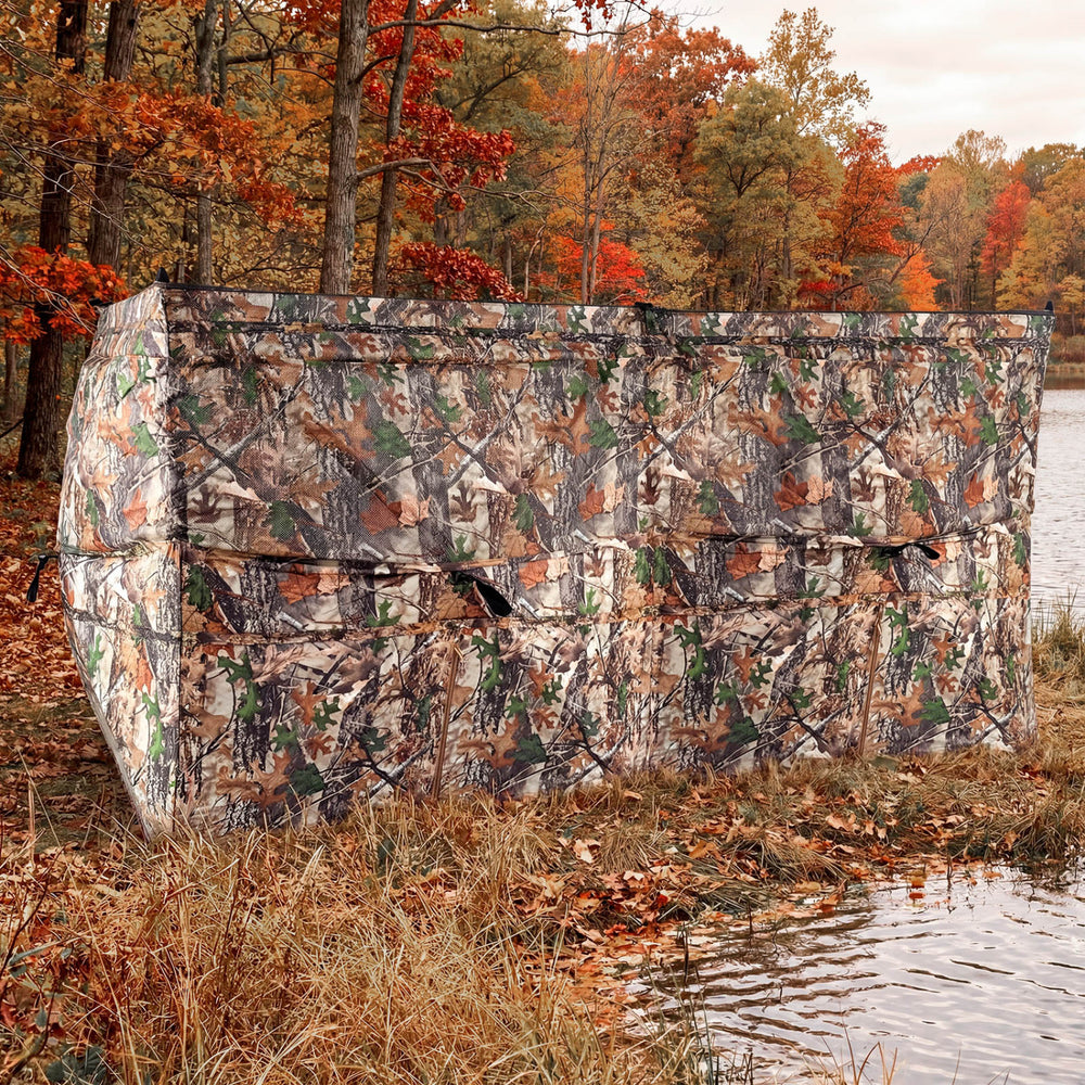 Pop-up hunting blind with camouflage pattern, adjustable windows, and dog doors for 1-3 people by the water.