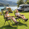 Two portable zero gravity chairs in gray with cup holder trays, set up for relaxing outdoors by a lake.