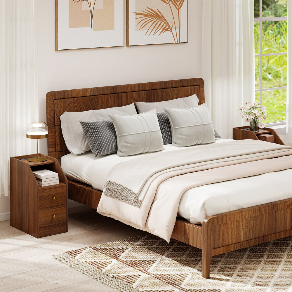 Walnut side end table with charging station, two drawers, and open compartment for organized storage beside a bed.