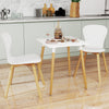Square dining table with white surface and wooden legs, featuring adjustable foot pads for stability in small kitchens.