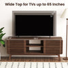 Walnut TV stand with sliding doors, adjustable shelves, and splayed rubber wood legs for TVs up to 65 inches.