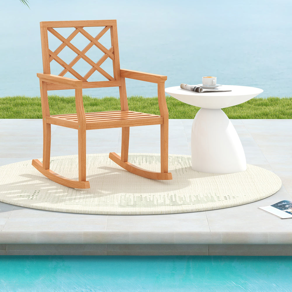 Teak wood rocking chair with slatted seat and backrest, perfect for outdoor relaxation by the poolside.